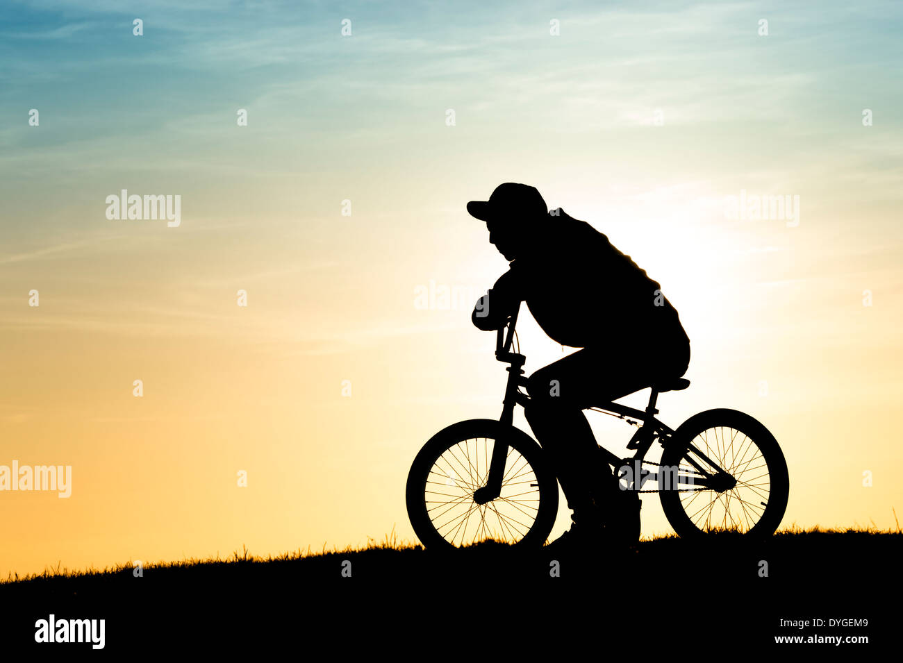 Giovane uomo seduto sul suo BMX bike. Silhouette Foto Stock