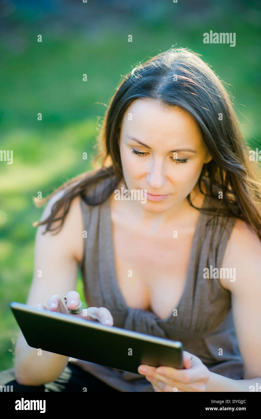 Frau sitzt mit Tablet in der Wiese - donna con la compressa nel prato Foto Stock