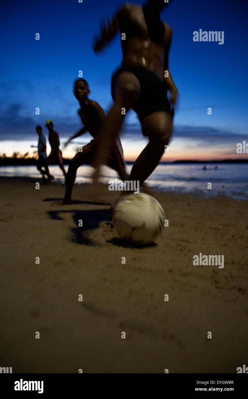 Il calcio brasiliano i giocatori di calcio in esecuzione durante la notte sulla spiaggia in una sfocatura in Nordeste Bahia Brasile Foto Stock