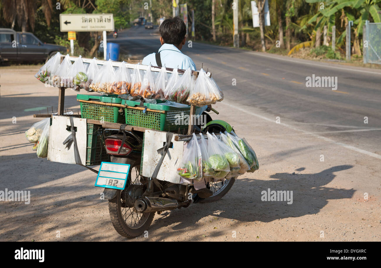 L uomo sulla moto di vendita di alimenti in sacchetti di plastica della Thailandia Foto Stock