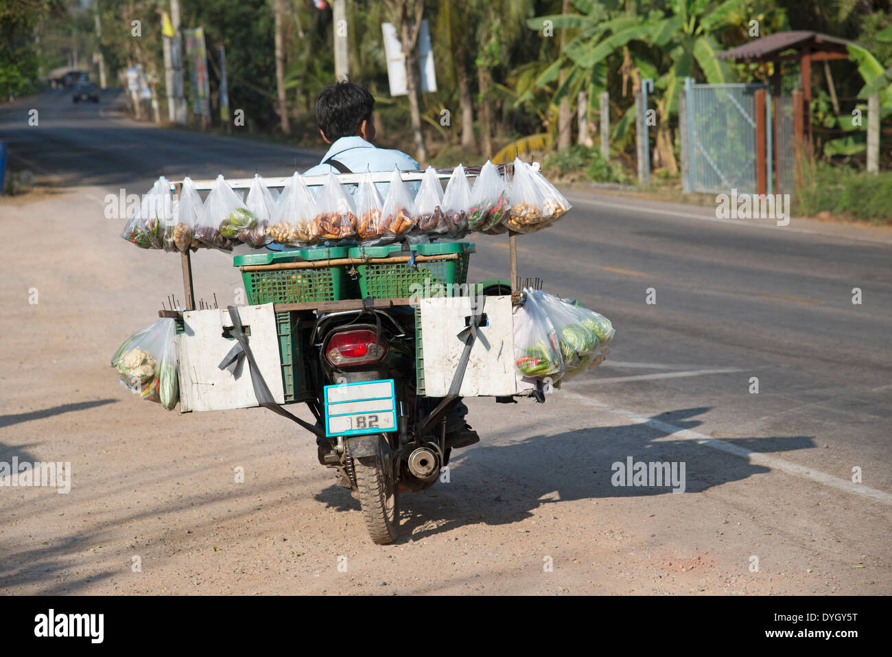 L uomo sulla moto di vendita di alimenti in sacchetti di plastica della Thailandia Foto Stock