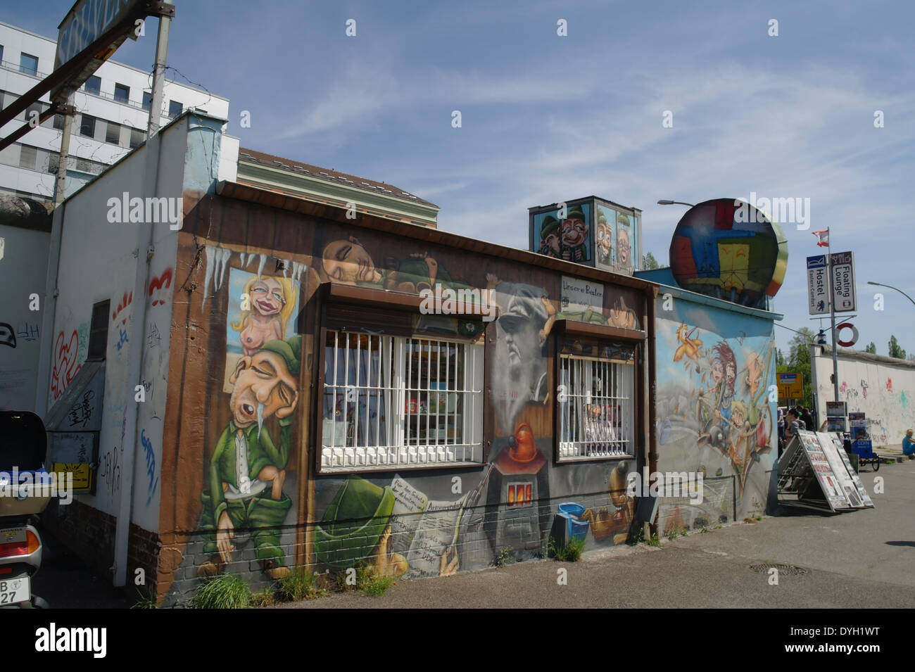 Cielo blu vista obliqua souvenir passaporto DDR stamping shop, con immagini di personaggi animati muri dipinti, la East Side Gallery di Berlino Germania Foto Stock