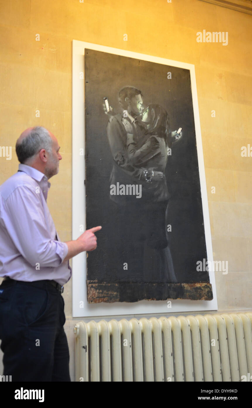 'Mobile di amanti che si suppone essere creato dall'artista di strada Banksy, apparso su una parete in St Judes a Bristol e aver rimosso è ora in vista nel Bristol City Museum NEL REGNO UNITO .la proprietà di questa immagine è ancora da determinare. Ray Barnett Bristol Collection Manager di gallerie visto che puntano a questa opera d'arte. Credito: Robert Timoney/Alamy Live News Foto Stock