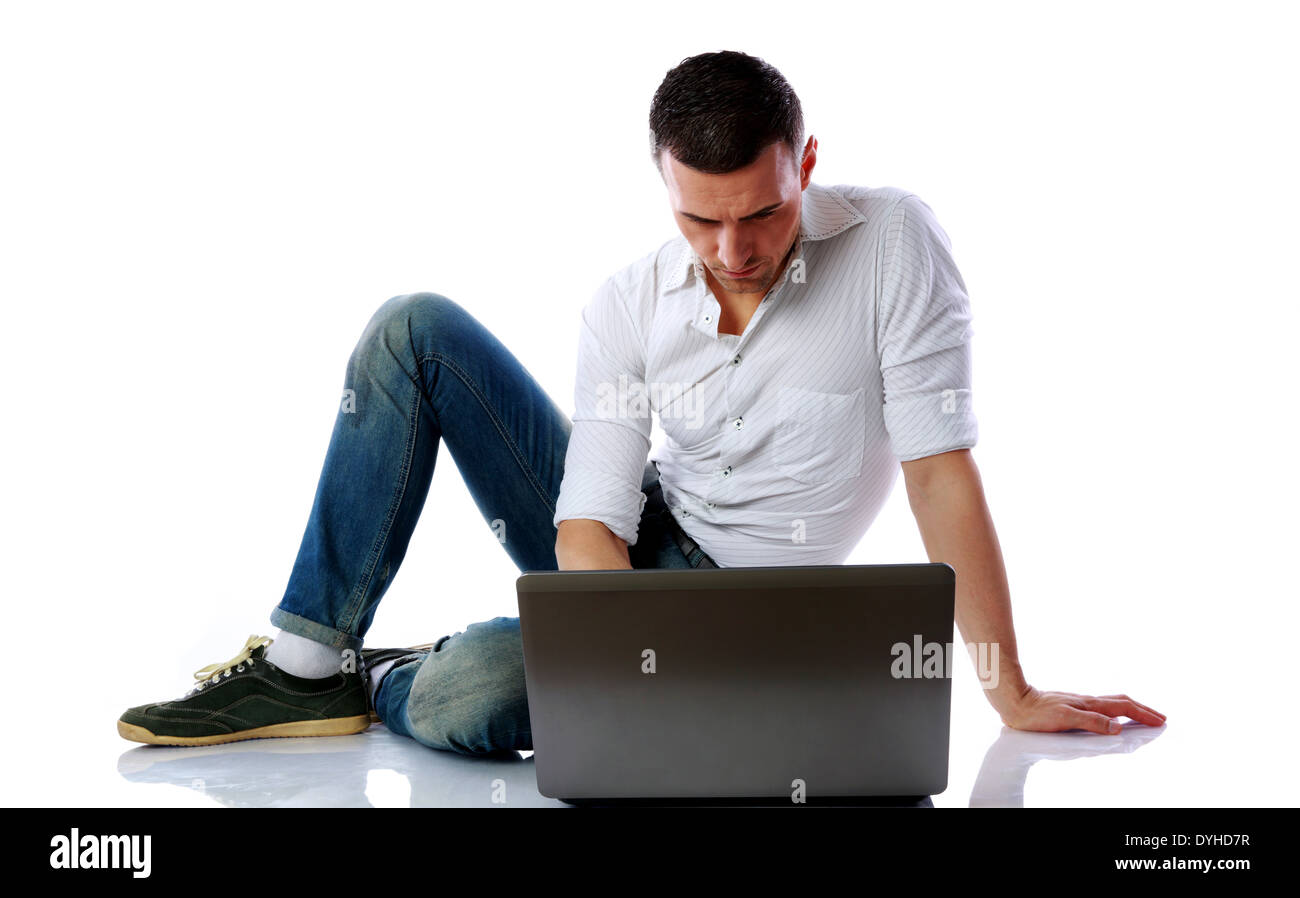 Fiducioso uomo utilizzando laptop sul pavimento su sfondo bianco Foto Stock