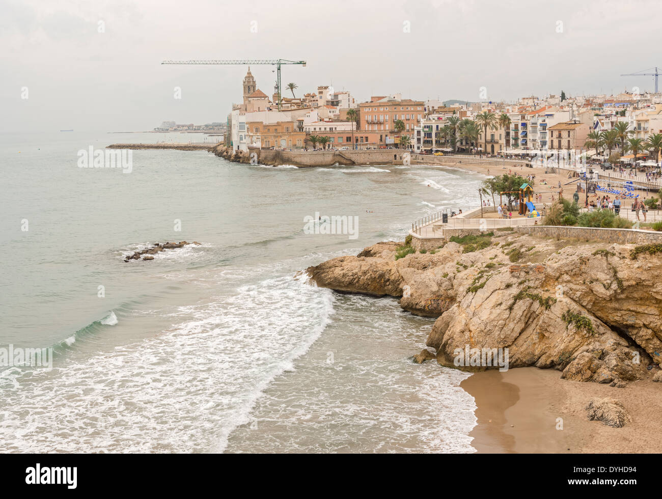Belle spiagge di Sitges sullo sfondo la chiesa di Sant Bartomeu & Santa Tecla. Le persone godono di acqua in una giornata di sole Foto Stock
