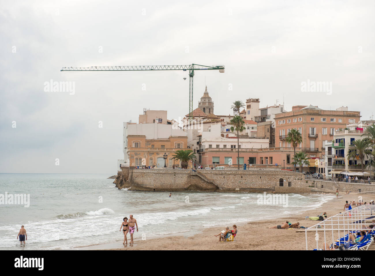 Belle spiagge di Sitges sullo sfondo la chiesa di Sant Bartomeu & Santa Tecla. Le persone godono di acqua in una giornata di sole Foto Stock