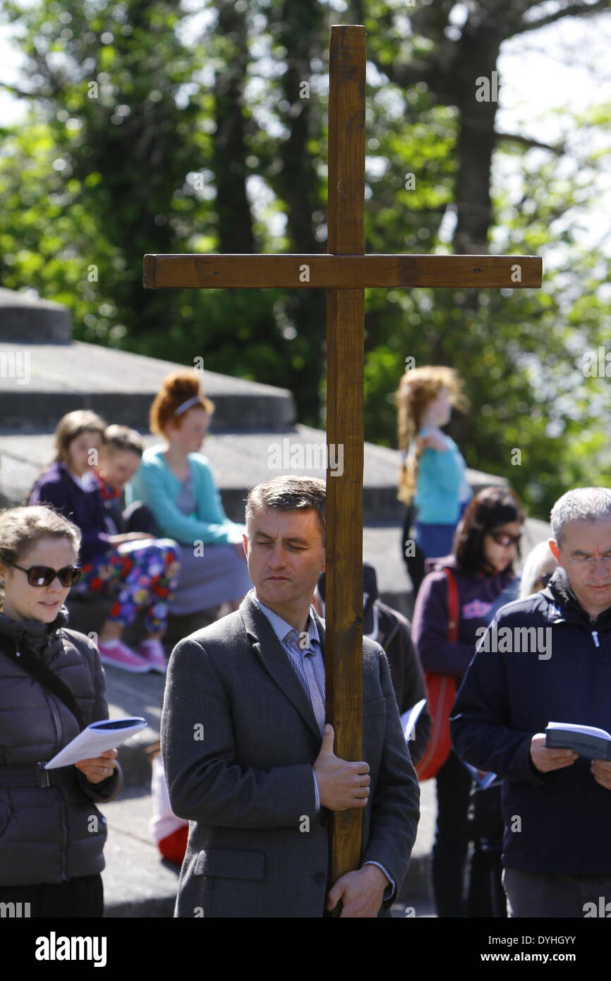 Dublino, Irlanda. Il 18 aprile 2014. Un pellegrino porta la grande croce di legno che conduce la processione. L Arcivescovo di Dublino Diarmuid Martin, ha portato a diverse centinaia di pellegrini in corrispondenzà di alcune stazioni della croce' processione attraverso il Parco Phoenix e. Le stazioni con letture e canti e la meditazione dovrebbe ricordarci la passione e la crocifissione di Gesù Cristo. Credito: Michael Debets/Alamy Live News Foto Stock
