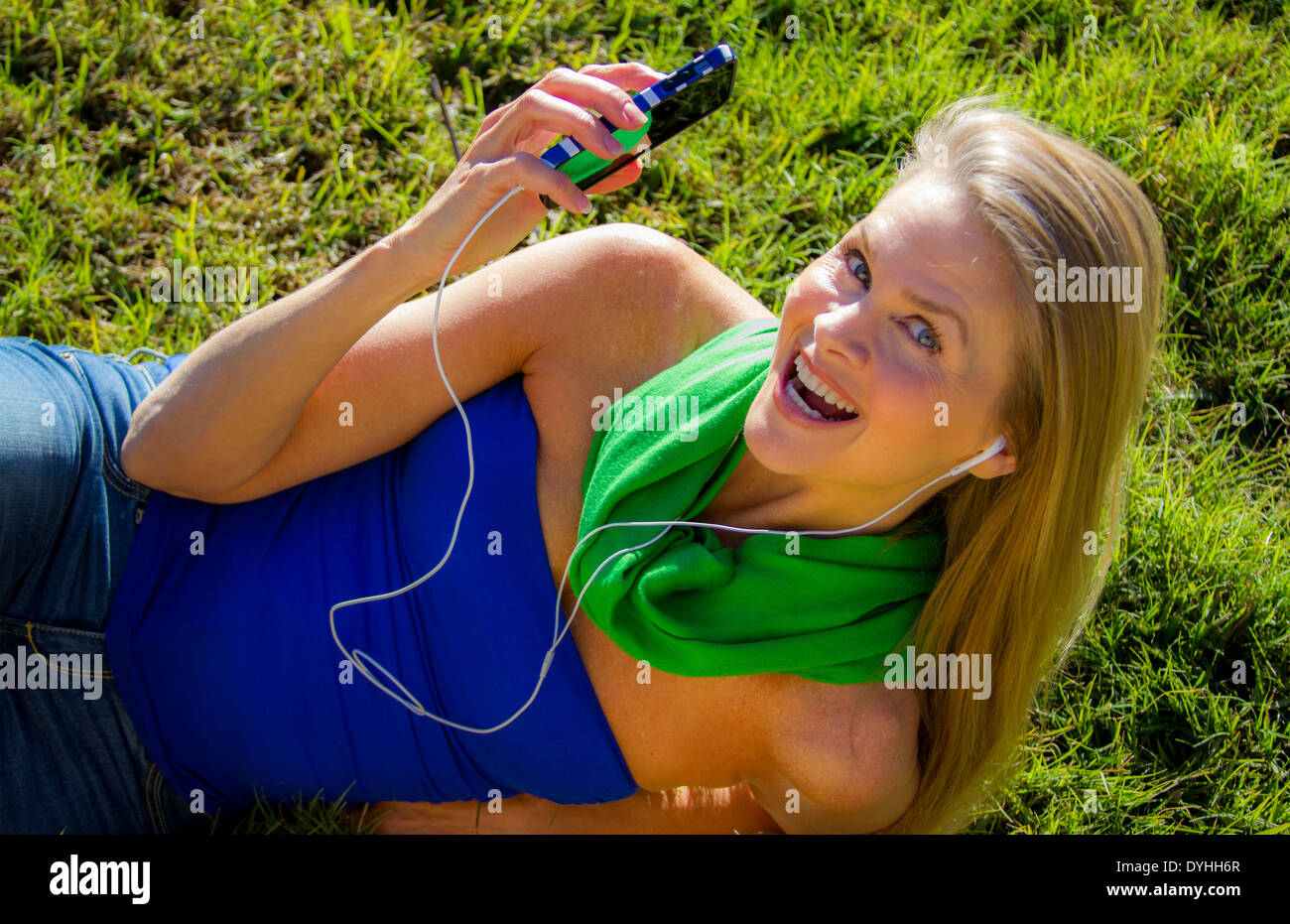 Bella bionda donna di mezza età in ascolto di musica su iPhone LETTORE MP3 con cuffie Foto Stock