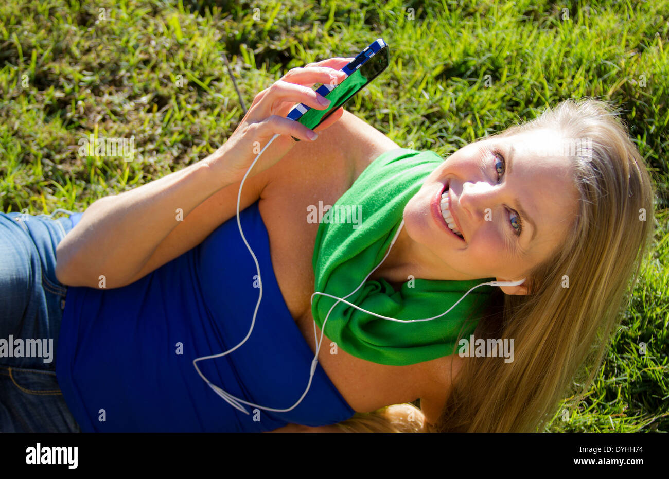 Bella bionda donna di mezza età in ascolto di musica su iPhone LETTORE MP3 con cuffie Foto Stock