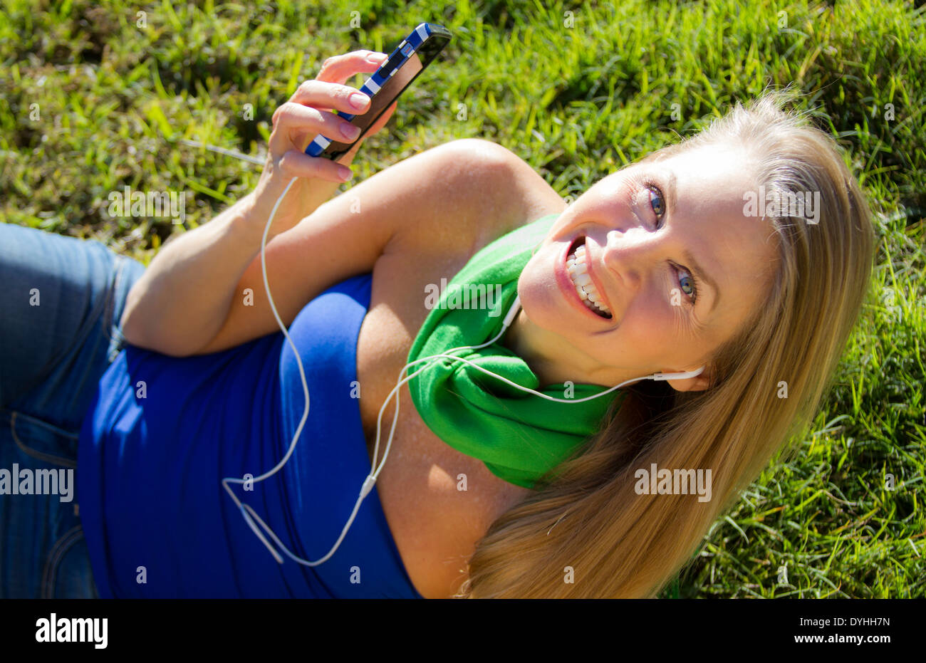 Bella bionda donna di mezza età in ascolto di musica su iPhone LETTORE MP3 con cuffie Foto Stock
