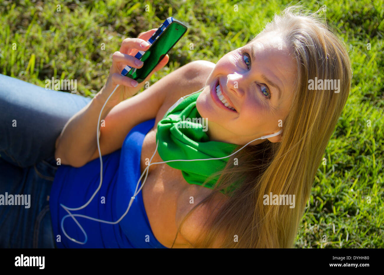 Bella bionda donna di mezza età in ascolto di musica su iPhone LETTORE MP3 con cuffie Foto Stock