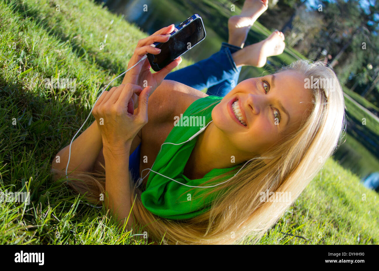 Bella bionda donna di mezza età in ascolto di musica su iPhone LETTORE MP3 con cuffie Foto Stock