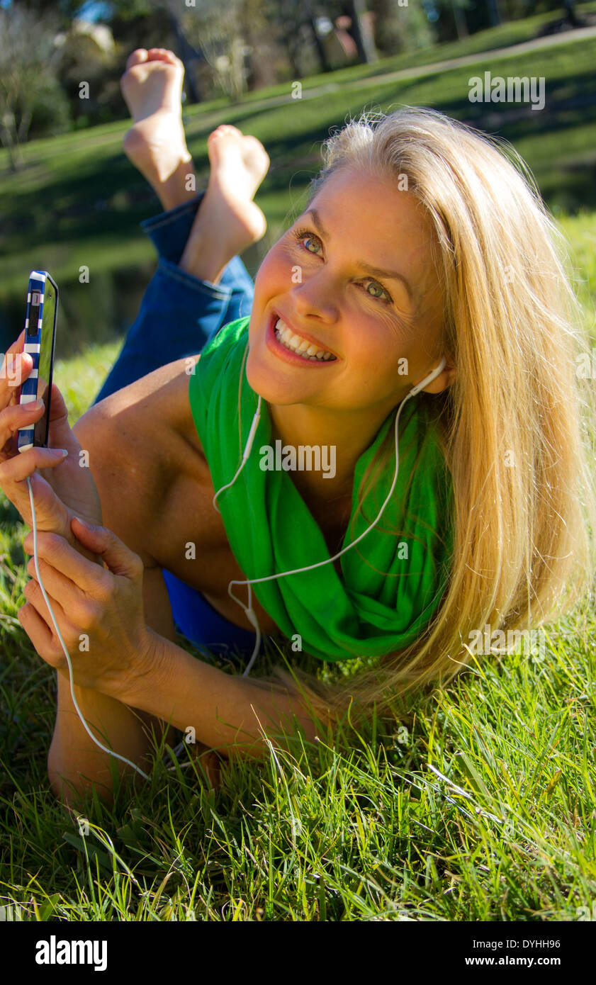 Bella bionda donna di mezza età in ascolto di musica su iPhone LETTORE MP3  con cuffie Foto stock - Alamy