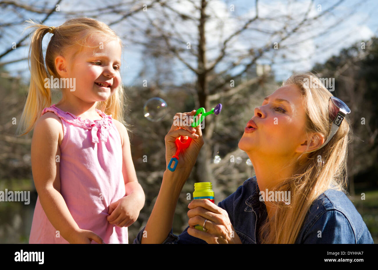 Madre e figlia a soffiare bolle in posizione di parcheggio Foto Stock