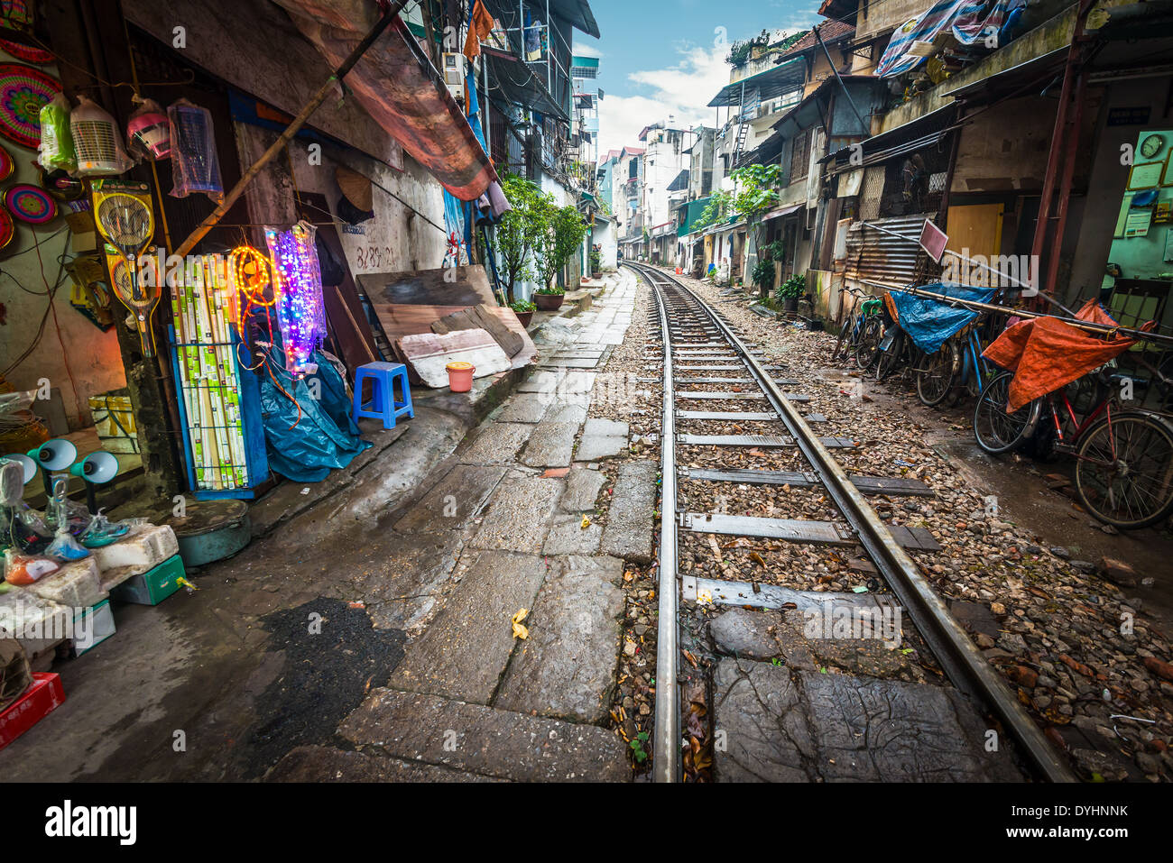 Vista prospettica della linea ferroviaria che corre lungo strade strette con case a Hanoi, Vietnam. Singolare soluzione del problema del trasporto. Foto Stock