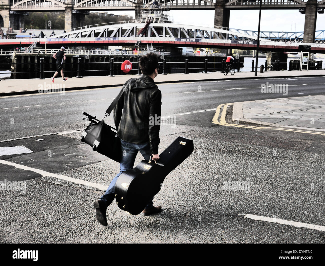 Creative / artistiche immagini fotografiche di uomo della strada di attraversamento durante il trasporto Custodia per chitarra, Quayside, Nr. Ponte girevole, Newcastle Regno Unito Foto Stock
