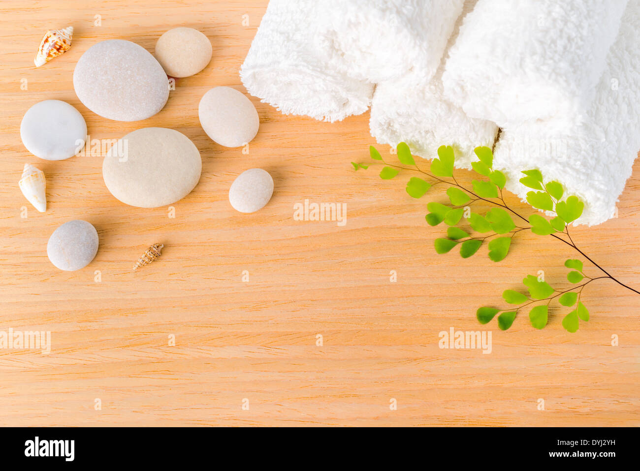 Concetto di Spa con pietre, conchiglie, ramo verde e asciugamani bianchi su sfondo di legno Foto Stock