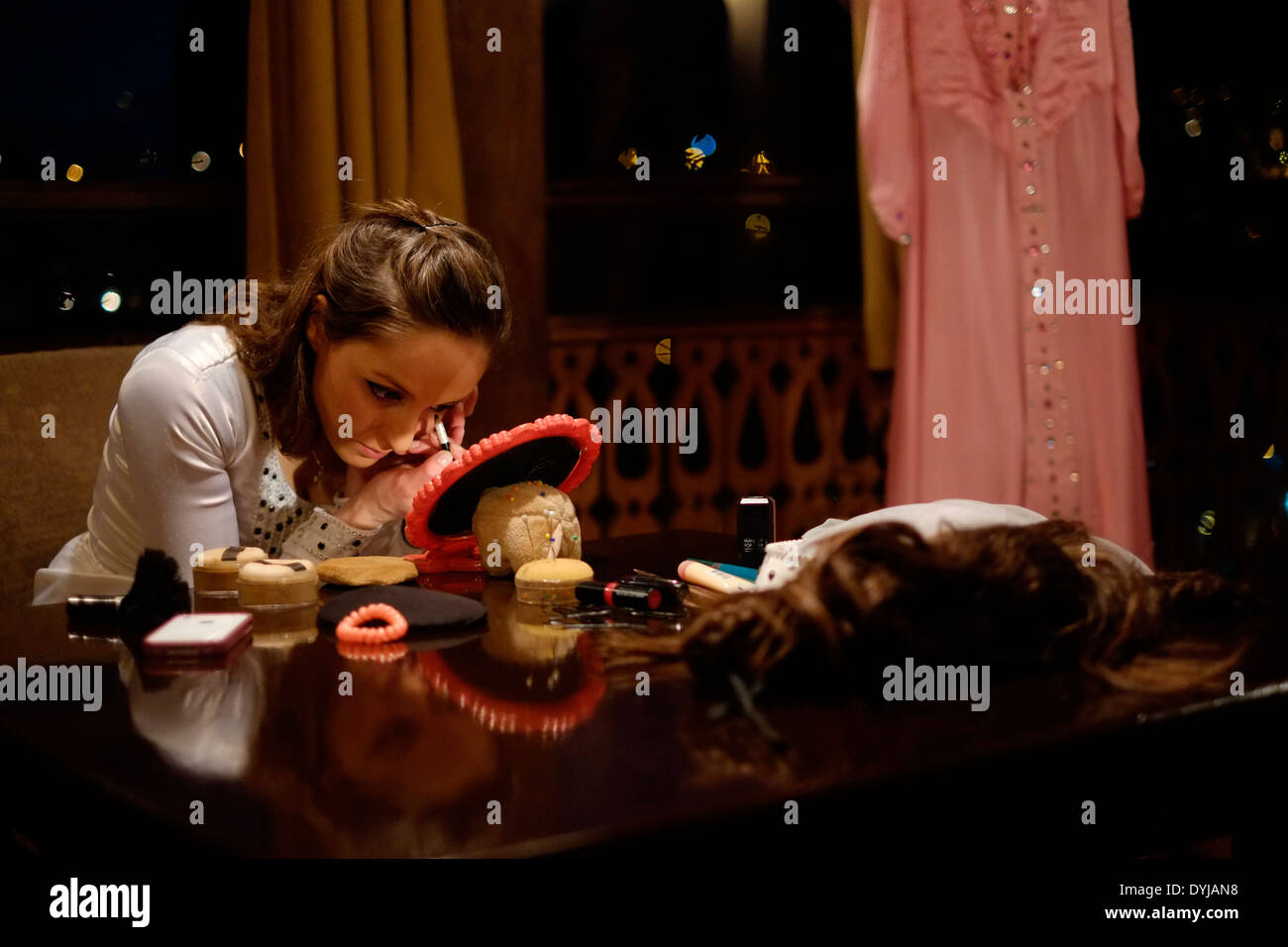 Un giovane ballerino guardando nello specchio e applicare il trucco sul sopracciglio mentre si prepara per una in stile georgiano tradizionale spettacolo di danza folkloristica in 'ombra di Metekhi' ristorante a Tbilisi, capitale della Repubblica di Georgia Foto Stock