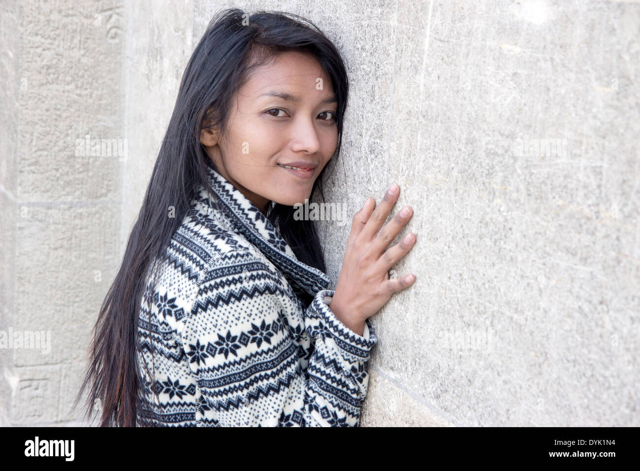 Donna appoggiata contro il muro di pietra Foto Stock