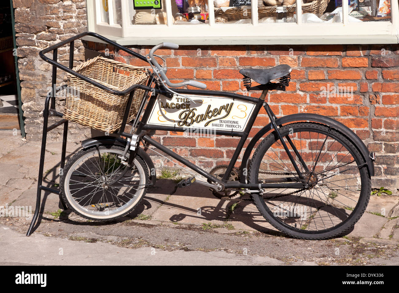 Fornai consegna bicicletta con cesto in vimini, Lacock, Wiltshire, Regno Unito Foto Stock