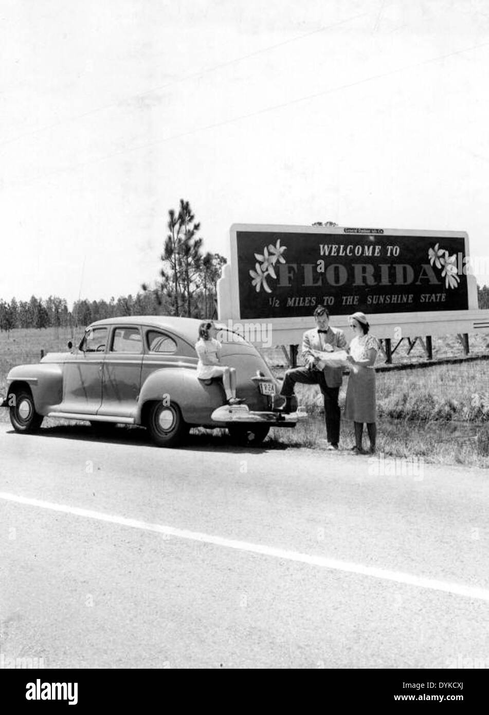 Una famiglia si ferma per guardare una mappa vicino al cartello di benvenuto della Florida, un simbolo iconico per i viaggiatori che entrano nello stato. L'immagine riflette l'atmosfera accogliente dell'industria turistica della Florida. Foto Stock
