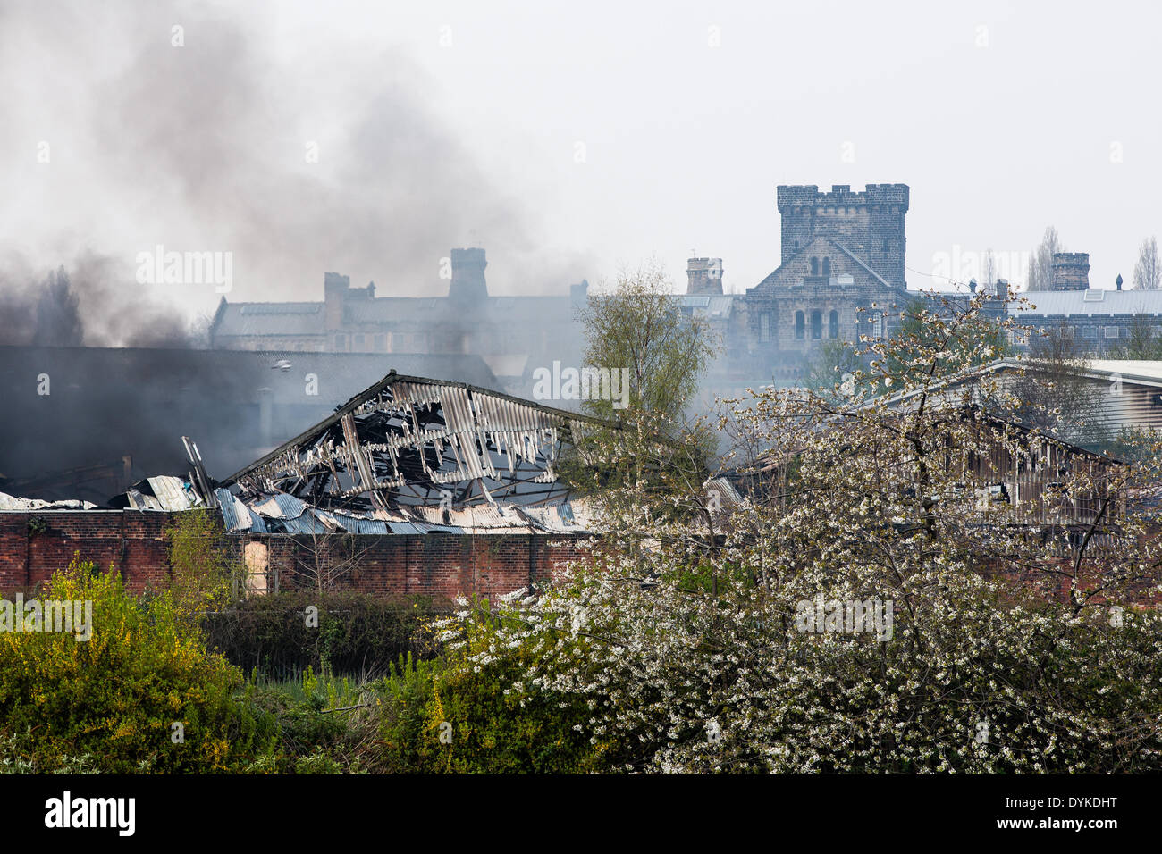Leeds, West Yorkshire, Regno Unito, 21 aprile 2014. Una coltre di fumo si blocca in aria come i vigili del fuoco continuano ad affrontare un incendio in Leeds industrial estate. Le torrette della storica Armley carcere può essere visto al di là della bruciata guscio dell'impianto. L'incendio scoppiato a circa 1,50 del mattino presso la sede di Tradpak un chimico di imballaggio e di impianto di riciclaggio nel Armley area della città. La fabbrica si trova vicino al centro della città e i residenti nelle vicinanze è stato detto di tenere le loro finestre e porte chiuse a causa delle sostanze chimiche potenzialmente tossiche implicate. Credito: Ian Wray/Alamy Live News Foto Stock