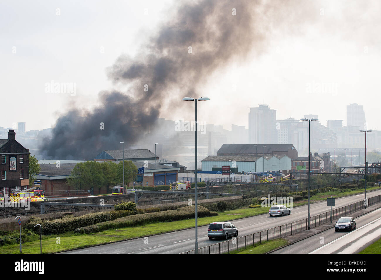 Leeds, West Yorkshire, Regno Unito, 21 aprile 2014. Armley Road. Una coltre di fumo si blocca in aria come i vigili del fuoco di affrontare un incendio di grandi dimensioni in un Leeds industrial estate. Dietro sono in alto gli sviluppi residenziali in e attorno al centro della città. L'incendio scoppiato a circa 1,50 del mattino presso la sede di Tradpak un chimico di imballaggio e di impianto di riciclaggio nel Armley area della città. La fabbrica si trova vicino al centro della città e i residenti nelle vicinanze è stato detto di tenere le loro finestre e porte chiuse a causa delle sostanze chimiche potenzialmente tossiche implicate. Credito: Ian Wray/Alamy Live News Foto Stock