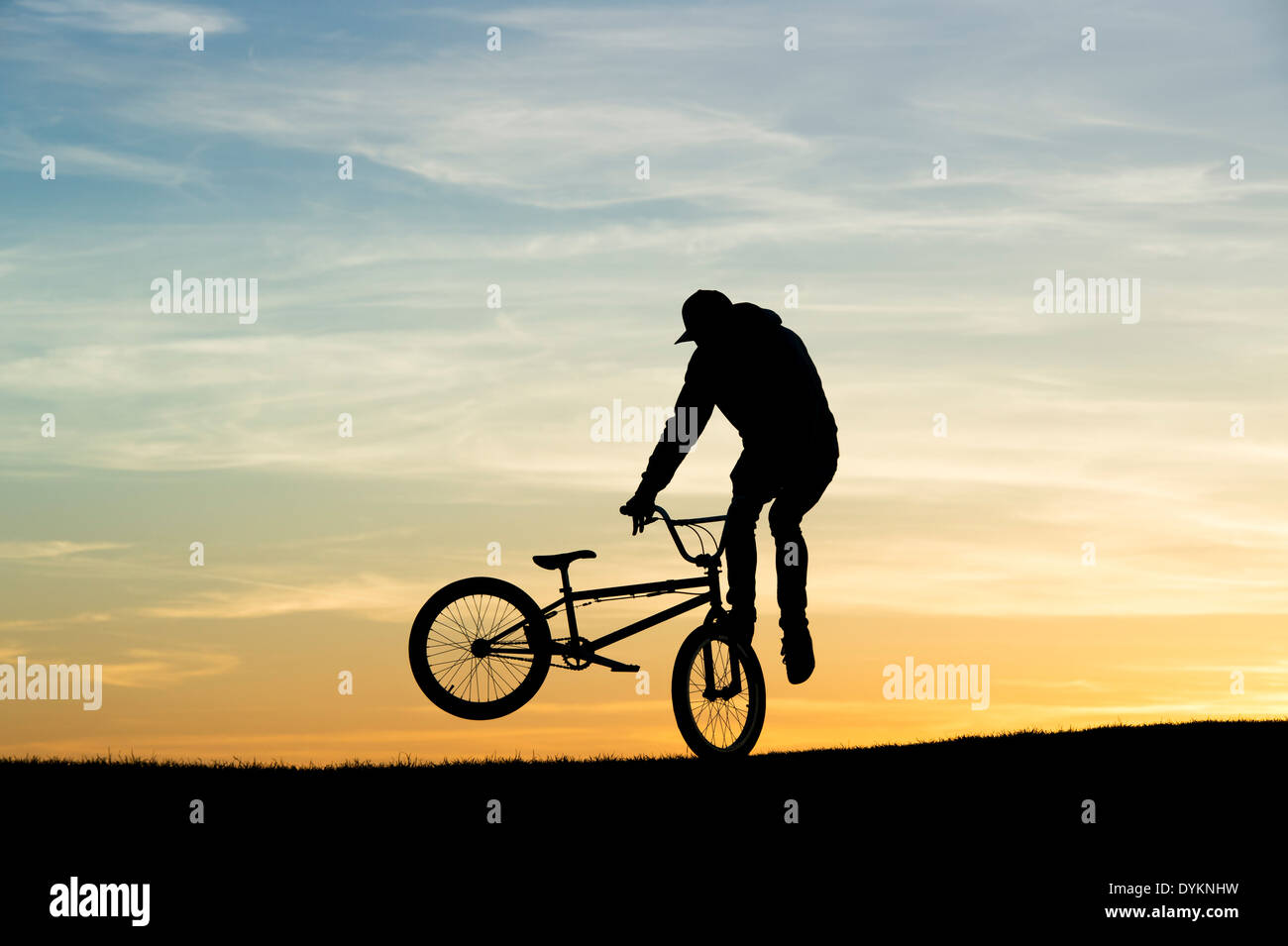 Giovane uomo facendo acrobazie sul suo BMX bike. Silhouette Foto Stock