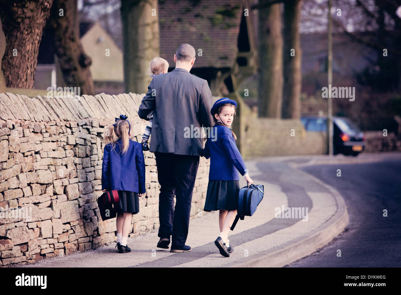 Un ben vestiti padre, tenendo le mani con i suoi figli e li a piedi a scuola Foto Stock