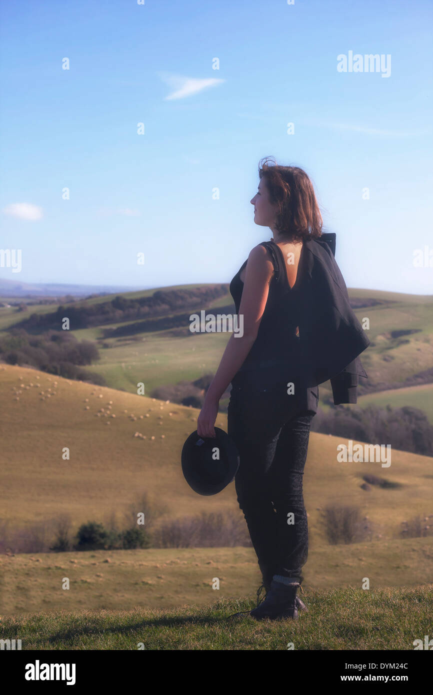 Un vestito nero ragazza è in piedi su una collina Foto Stock