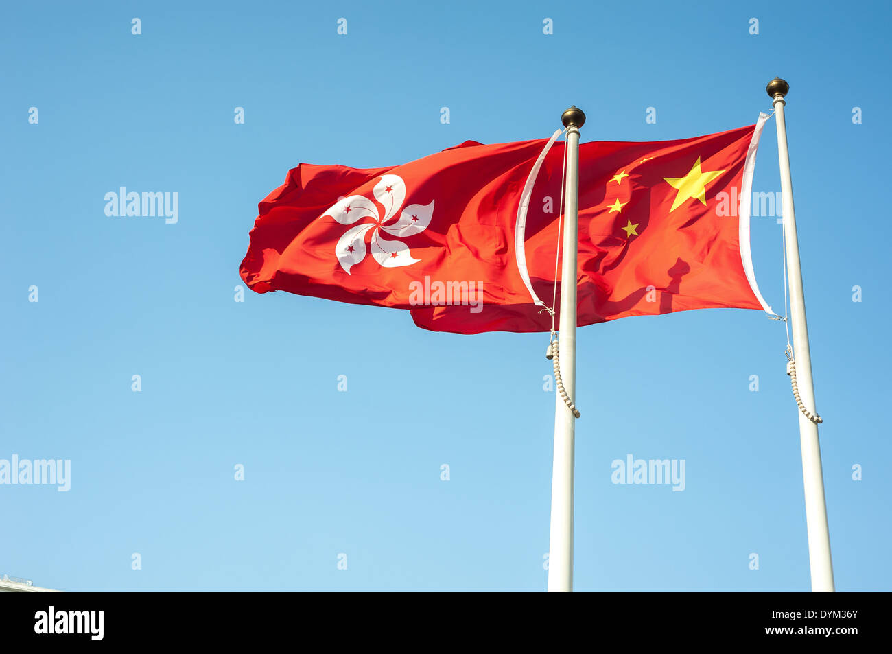 Hong Kong e la Cina le bandiere nazionali battenti contro un cielo blu Foto Stock