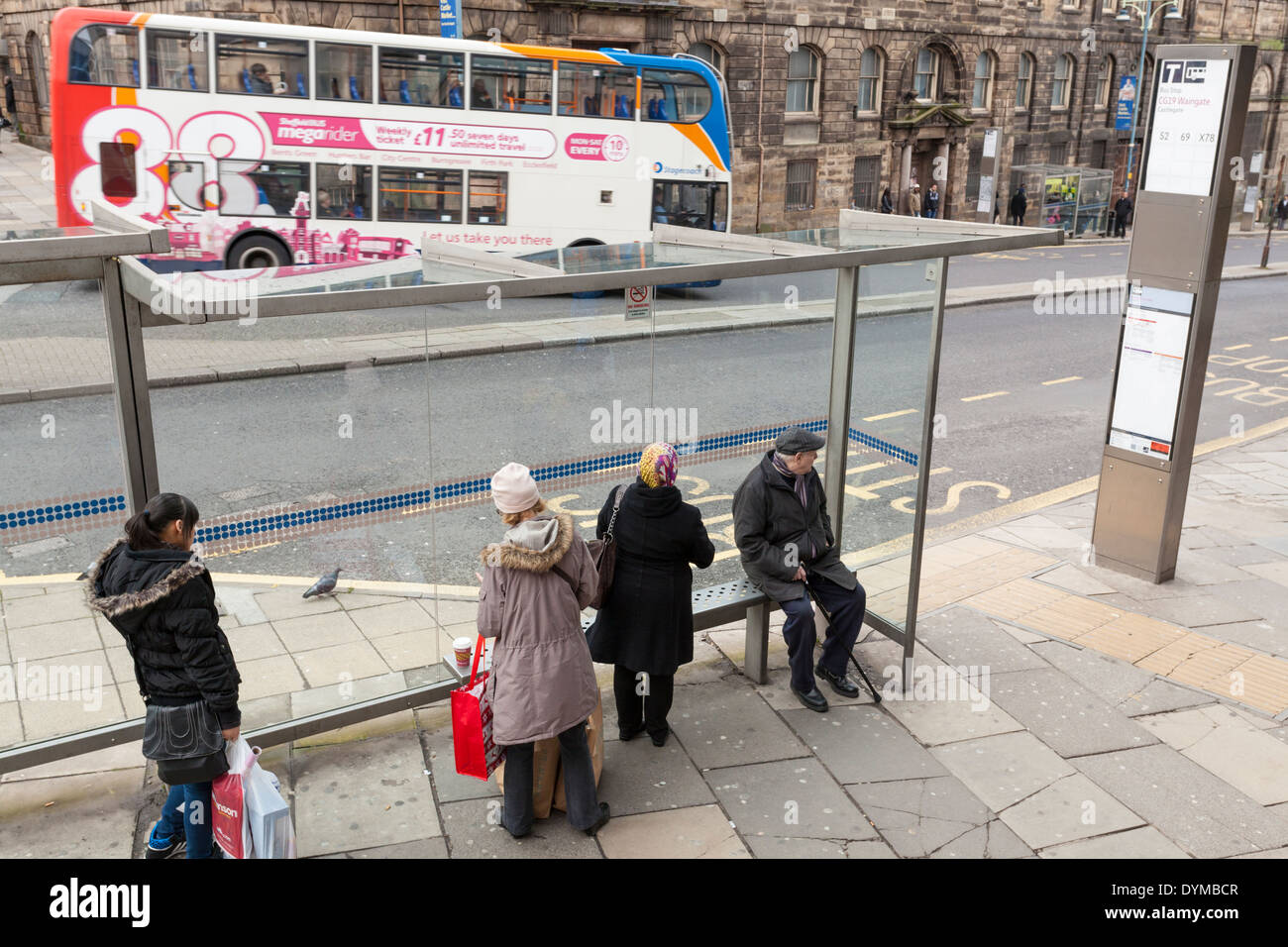 I mezzi di trasporto pubblici. Le persone in attesa di un autobus come uno passa attraverso la Street, Sheffield City Centre, nello Yorkshire, Inghilterra, Regno Unito Foto Stock