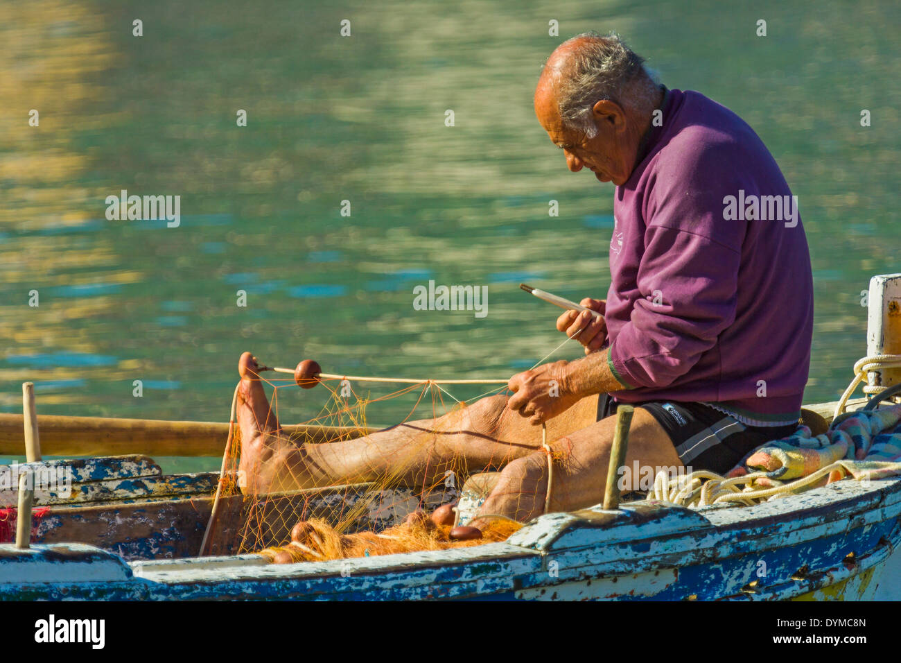 Fisherman rammendo un netto nella sua barca a questo storico popolare cittadina turistica; Cefalu, provincia di Palermo, Sicilia, Italia Foto Stock