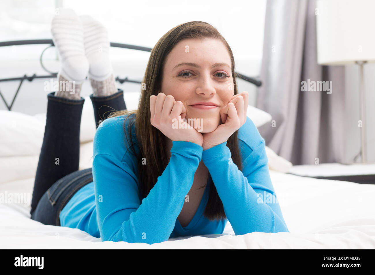 Ragazza adolescente giacente sul letto felice Foto Stock