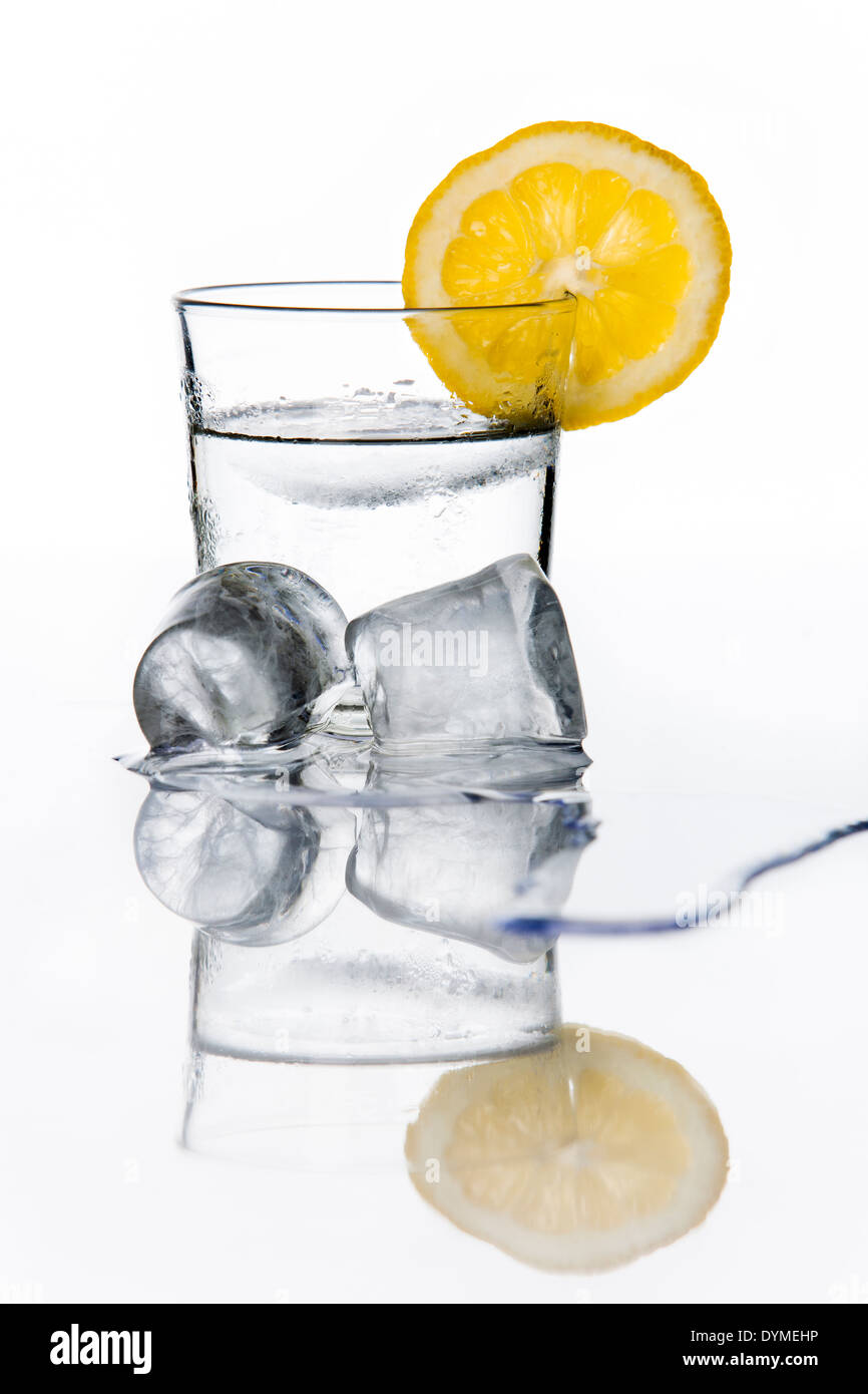 Bicchiere di acqua con una fettina di limone un cubetti di ghiaccio Foto Stock