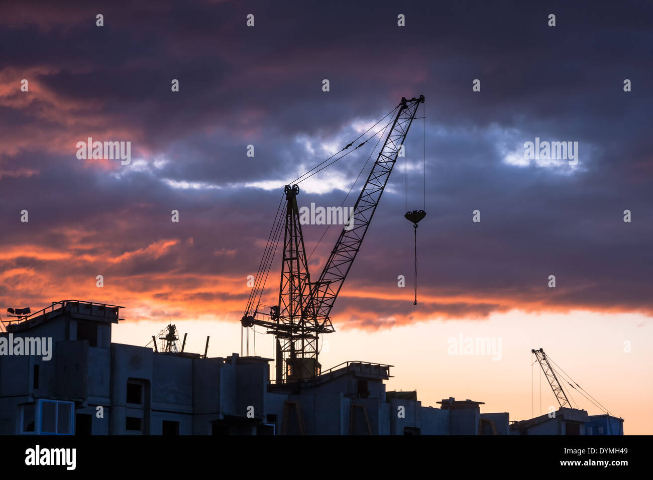 Silhouette di costruzione gru sul drammatico sfondo cielo al tramonto Foto Stock