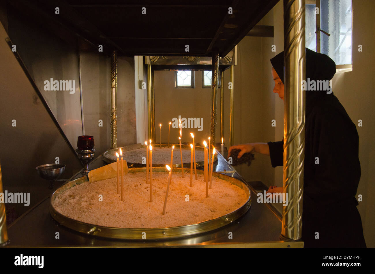 Nun accendendo candele presso il monastero di San Gerasimus, Cefalonia, Grecia Foto Stock