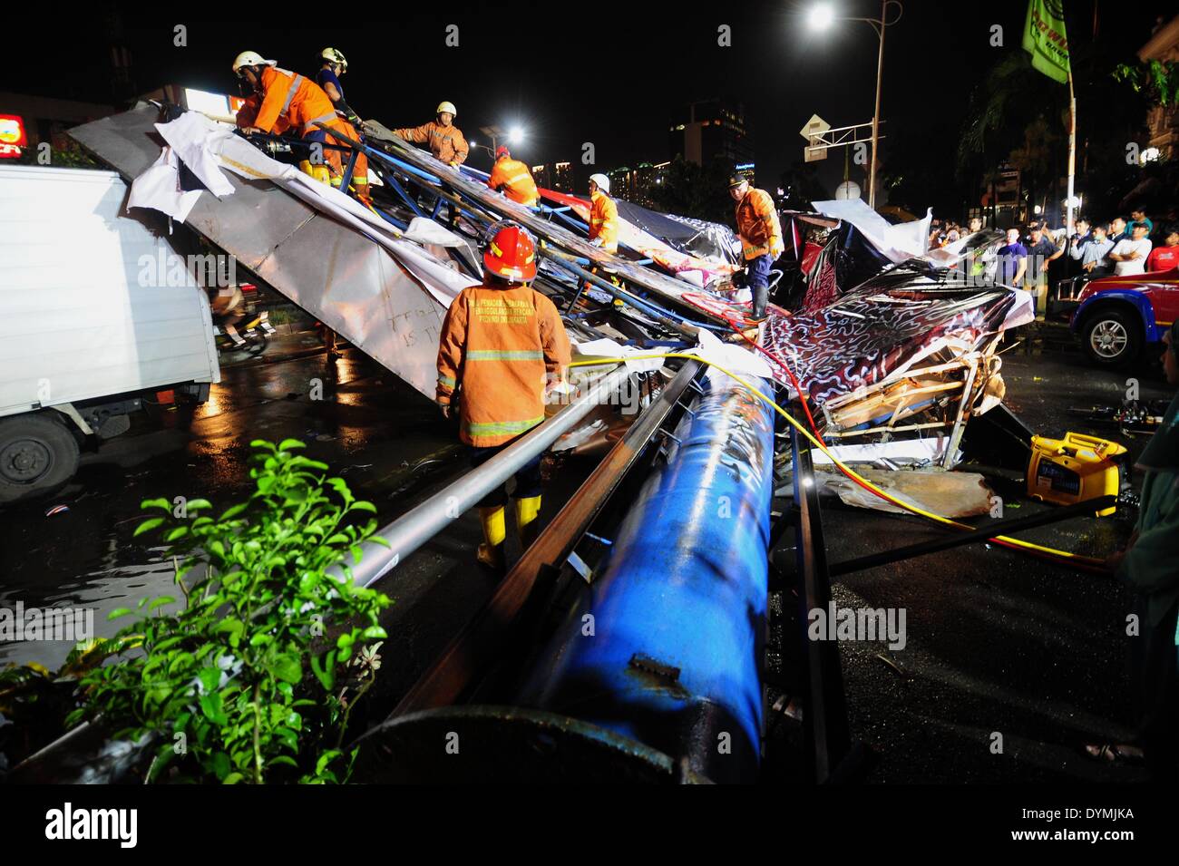 Jakarta, Indonesia. 22 apr 2014. I vigili del fuoco sono visibili su un cartellone che è crollato a causa di forte pioggia e forte vento a Giacarta, capitale dell'Indonesia, il 22 aprile 2014. Tabellone per le affissioni sopraffatto tre auto e una motocicletta, facendo in modo che due persone ferite e il traffico lungo la marmellata. Credito: Zulkarnain/Xinhua/Alamy Live News Foto Stock