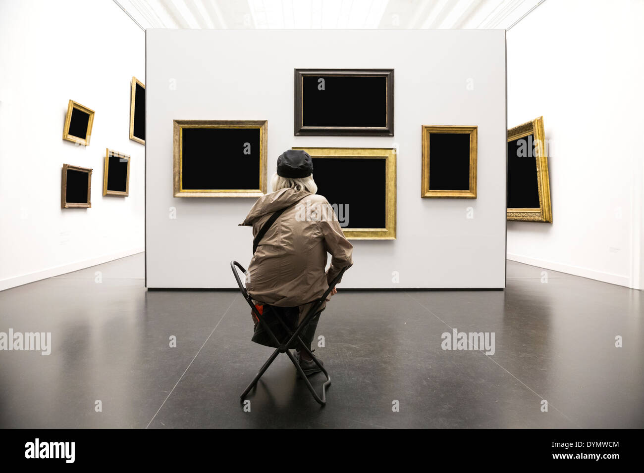Old Lady si siede di fronte a parete con dipinti nella galleria d'arte Foto Stock
