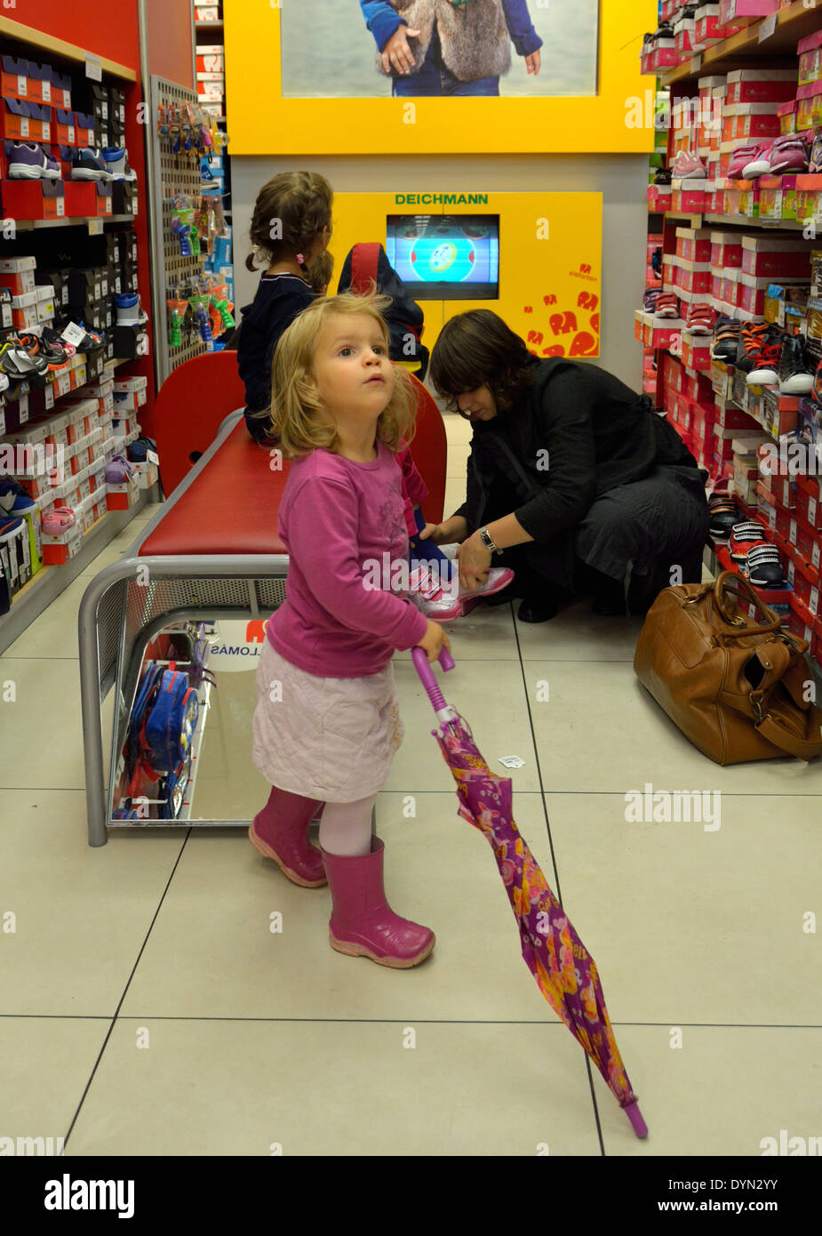 Bambina in una calzatura negozio con ombrellone Foto Stock