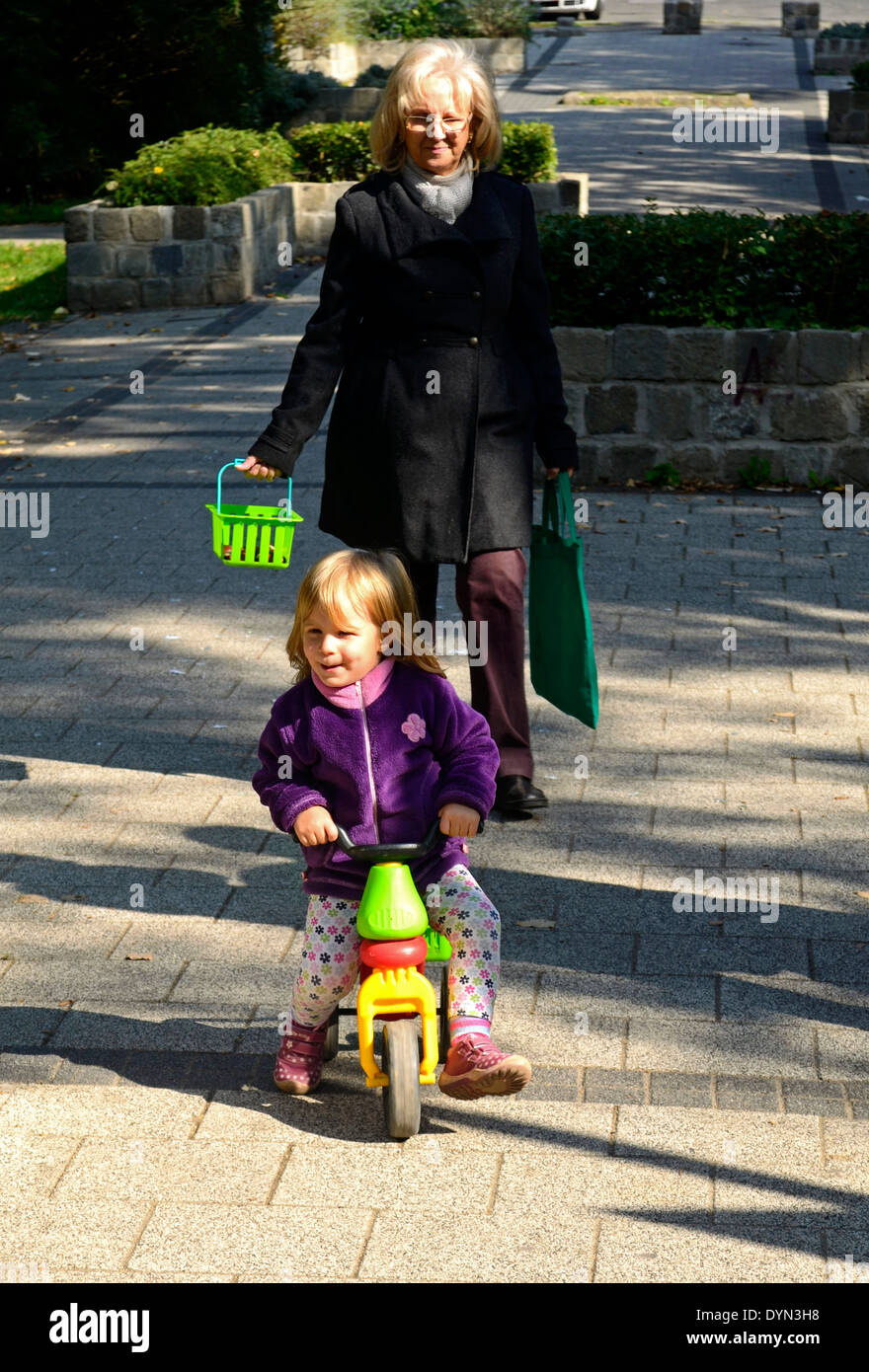 Ragazza sui tricicli nel parco con Grandmama Foto Stock