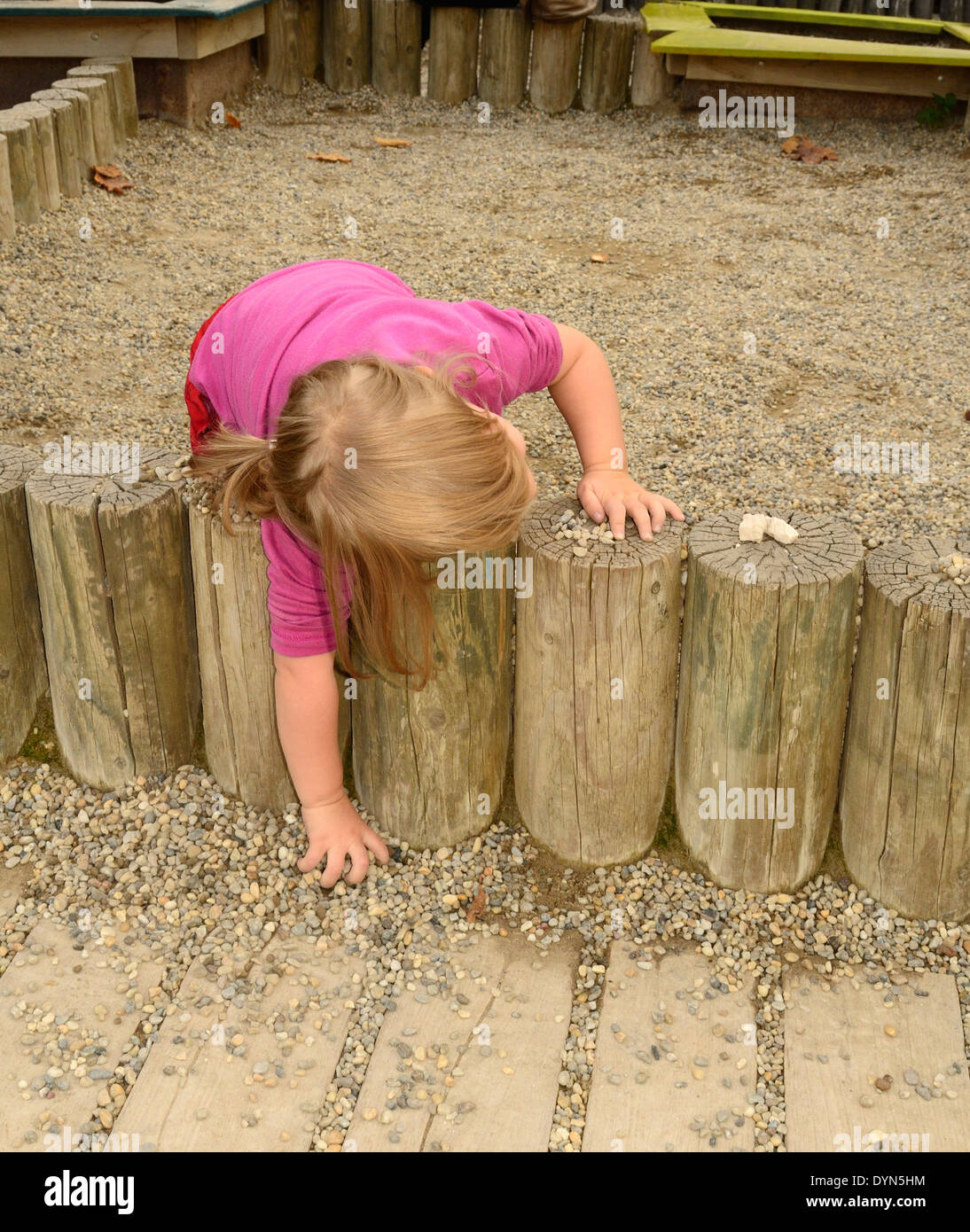 Bambina giocando con i ciottoli presso il parco giochi Foto Stock