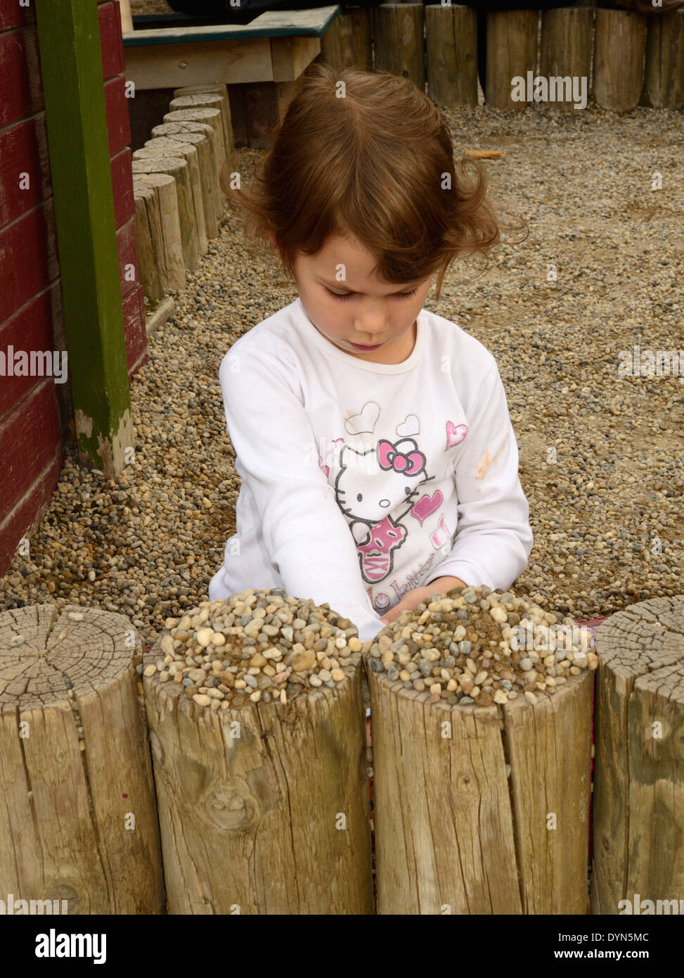Bambina giocando con i ciottoli presso il parco giochi Foto Stock