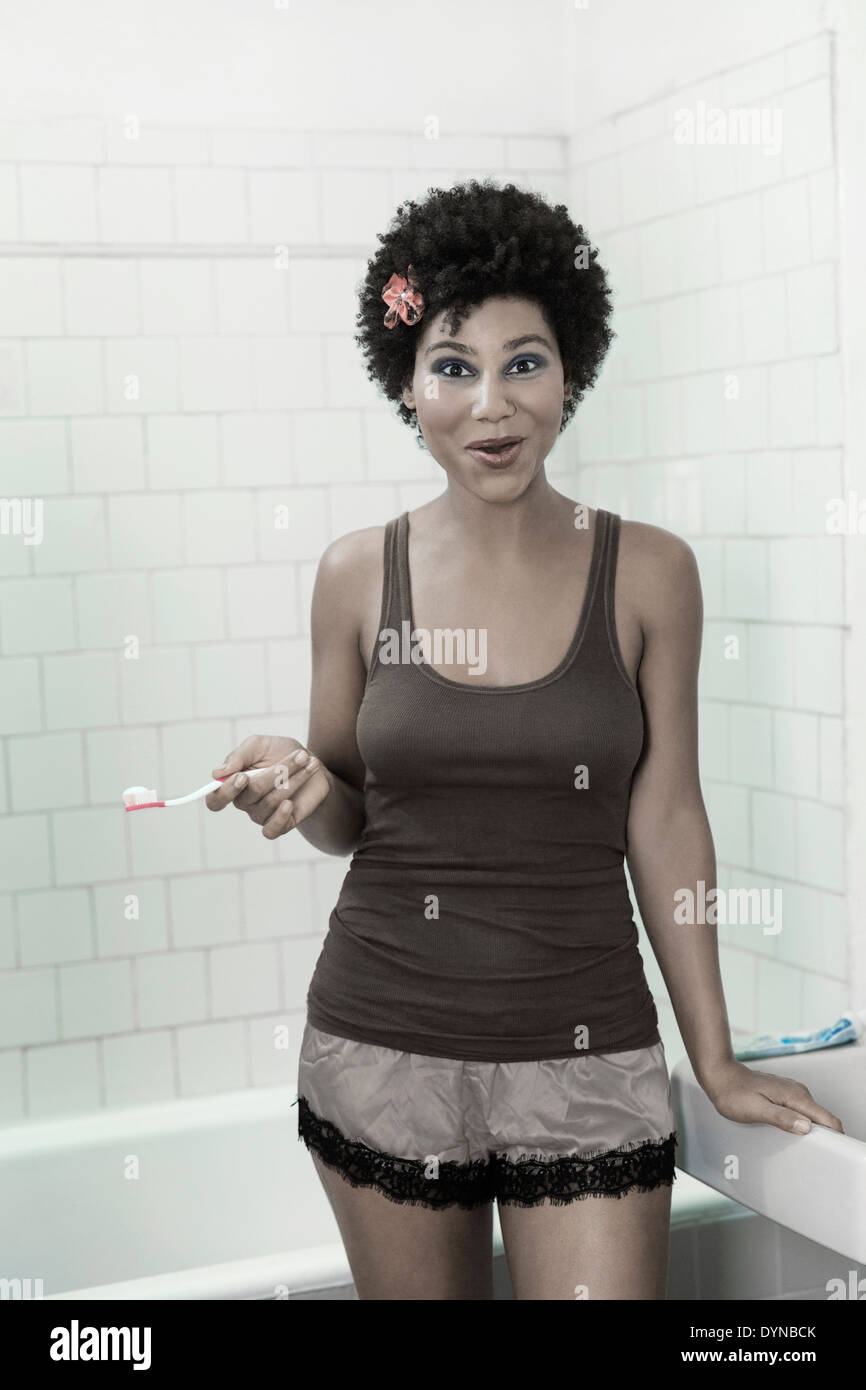 Donna spazzolare i suoi denti nella stanza da bagno Foto Stock