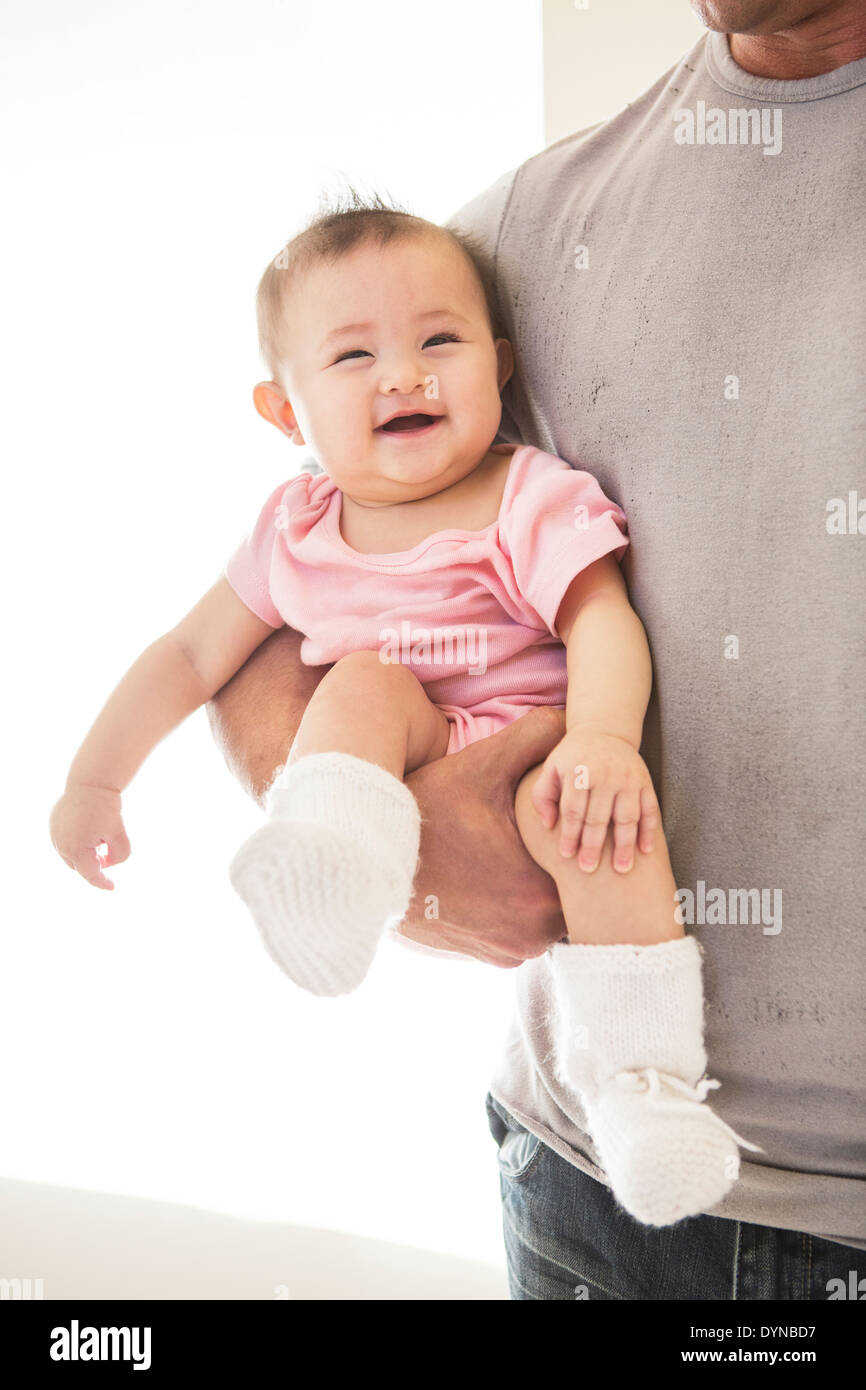 Padre che trasportano Laughing baby girl Foto Stock