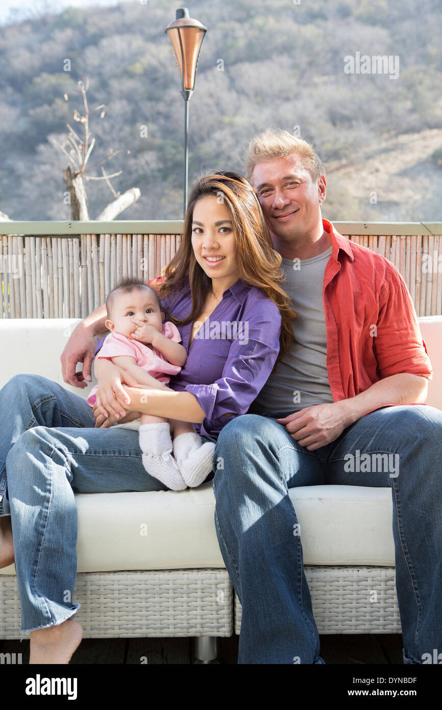 Famiglia sorridente sul patio divano Foto Stock