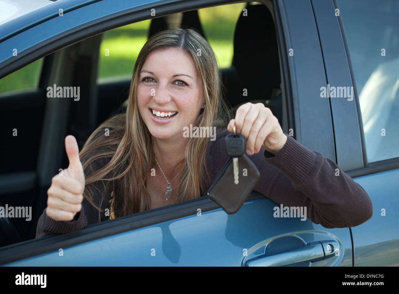 Donna sorridente è pendente al di fuori della finestra e mostra una chiave Foto Stock