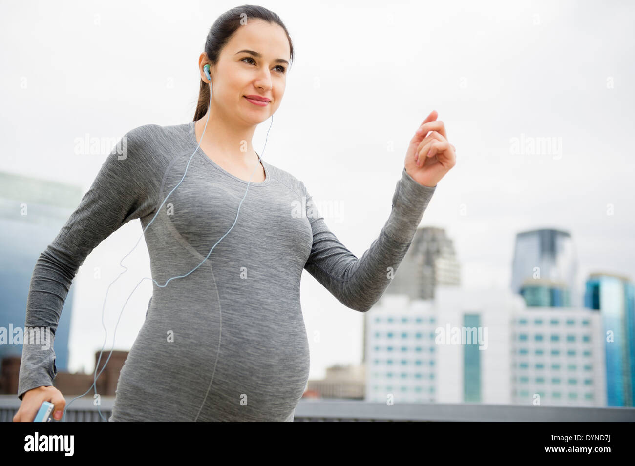 Incinta donna caucasica jogging sulla strada di città Foto Stock