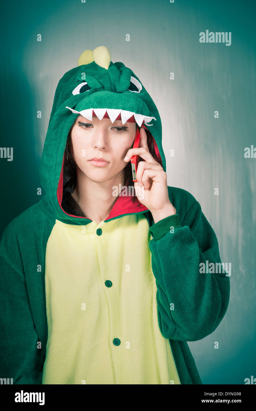 Grave donna in costume di dinosauri tenendo il telefono cellulare Foto Stock