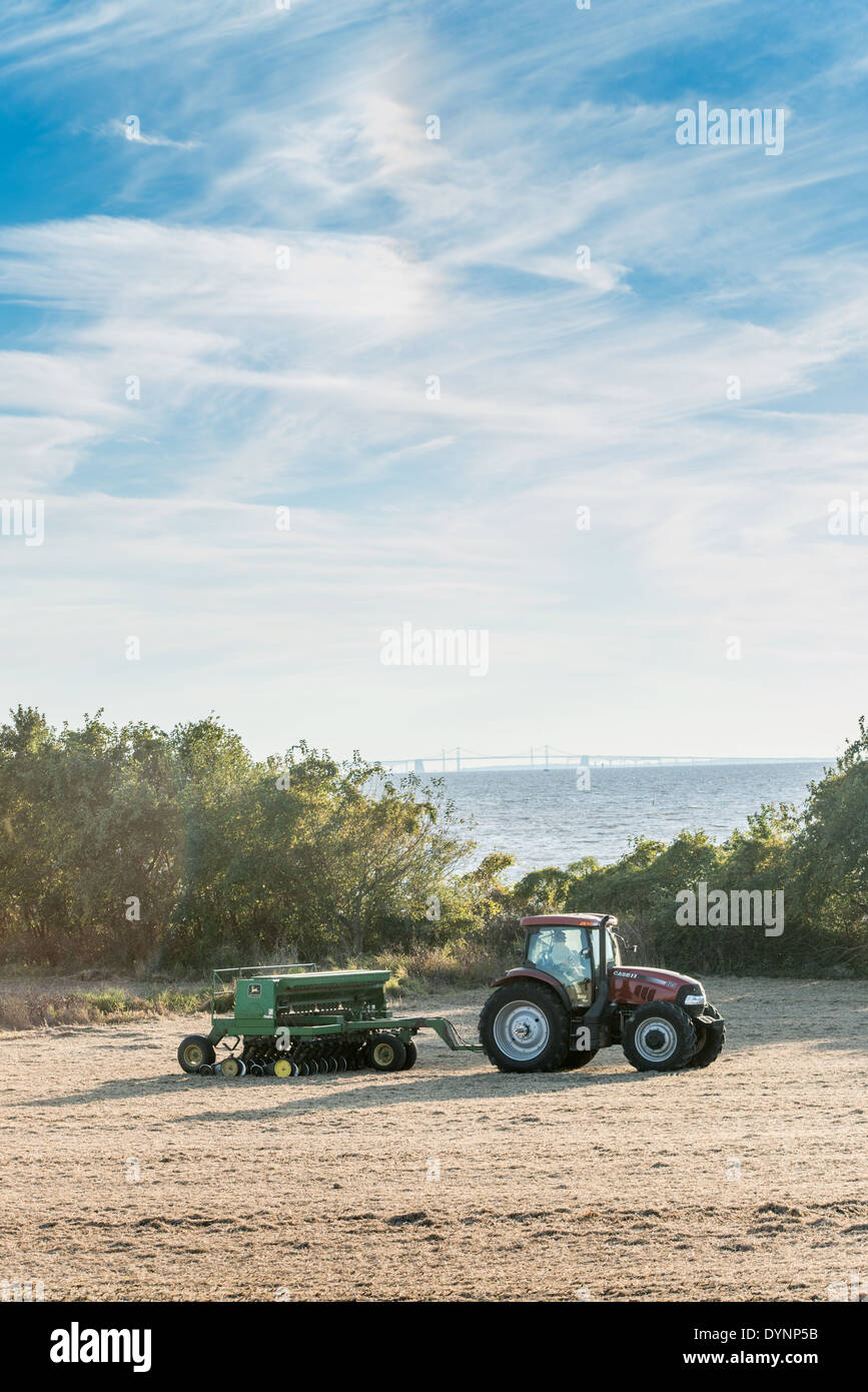 L'agricoltore nel trattore con il Bay Bridge in background Kent County MD Foto Stock